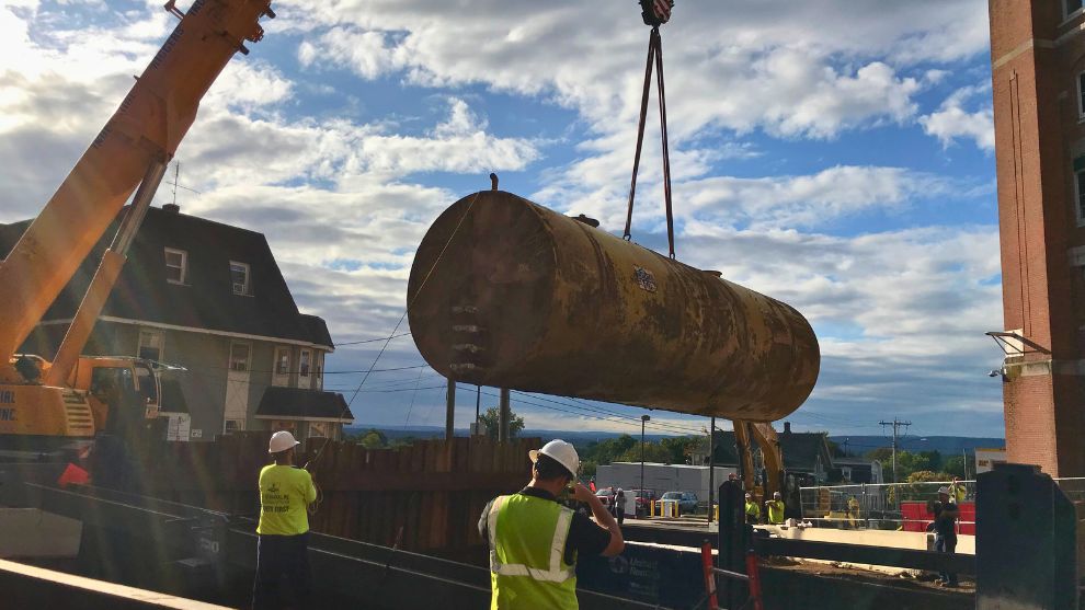 Structure and workers be ending near tank that is being removed