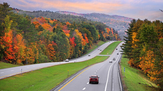 four lane highway in Vermont with orange and yellow foliage.