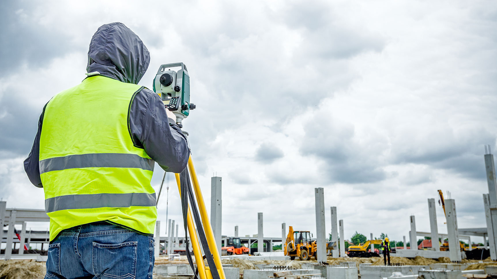 A close up of a person with a safety vest and surveying equipment