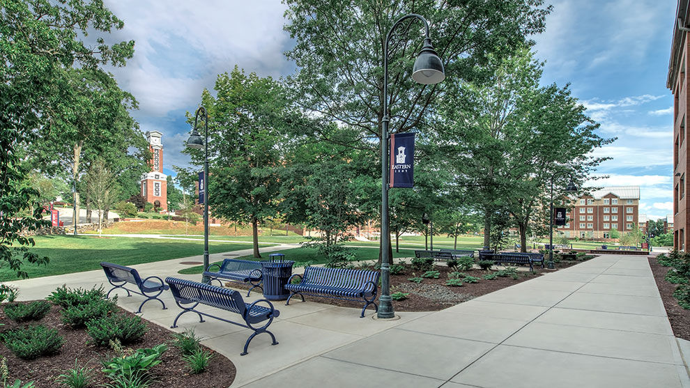 View of college campus with park benches sidewalk grass and trees