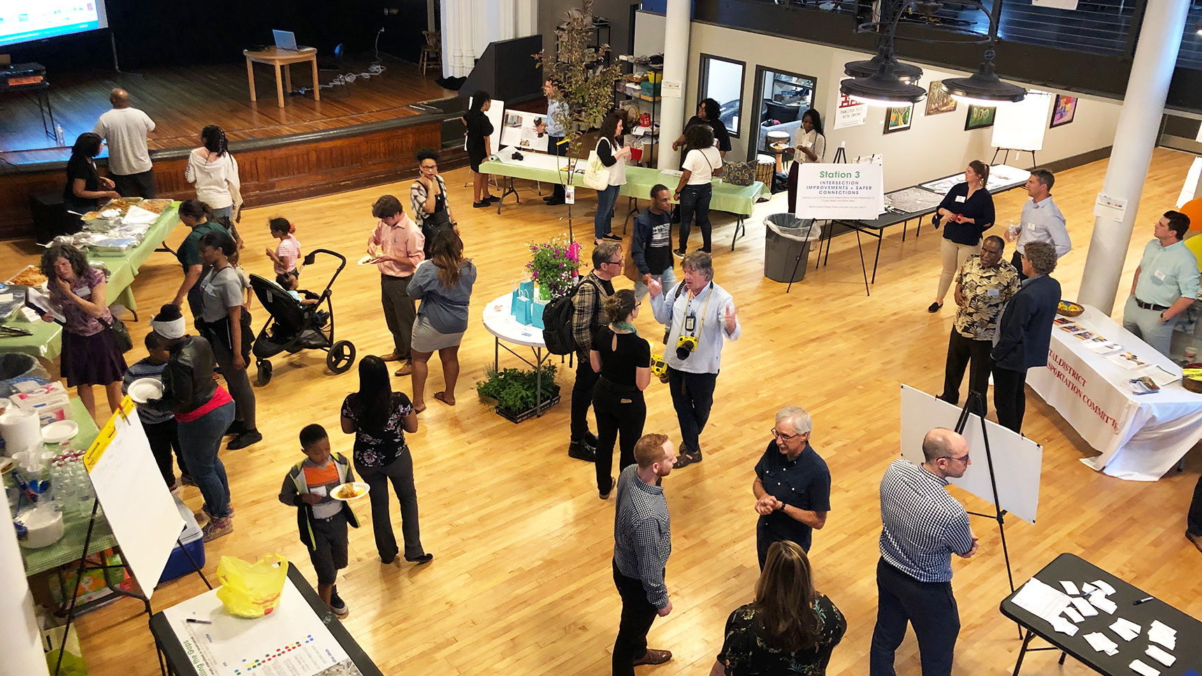 Large room with many people standing around talking at a community event