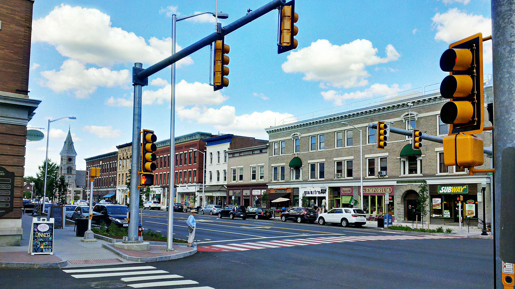 Street corner at busy intersection with someone waiting to cross in a crosswalk