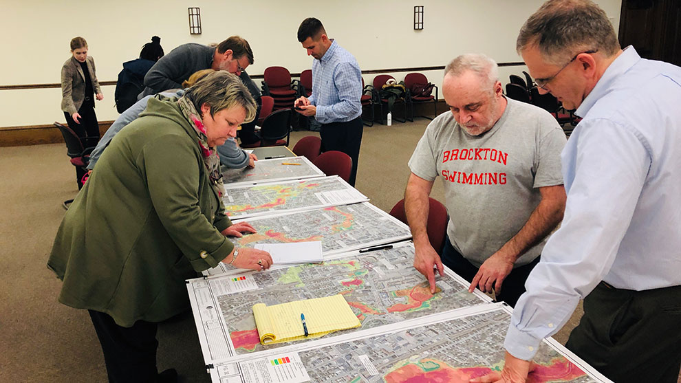 People at a community event standing at tables reviewing project plans