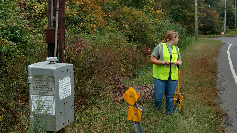 Woman in a safety vest on the side of the roadway