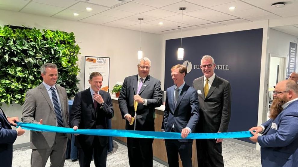 People standing in the reception area of Fuss & O'Neill's New Haven office with large scissors and ribbon getting ready for office dedication and ribbon cutting