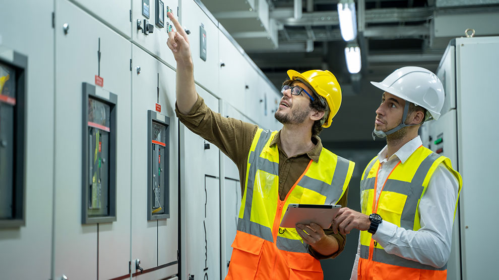 Two people in safety vests inspecting equipment