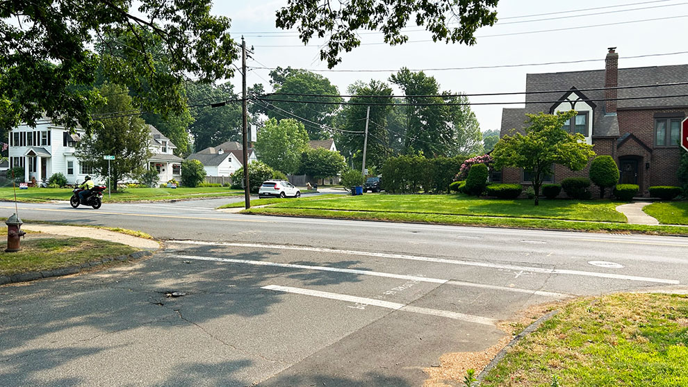 Motorcycle driving down route five with houses in the background