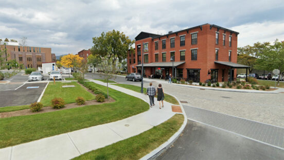 street view with two people walking on sidewalk and building in the background